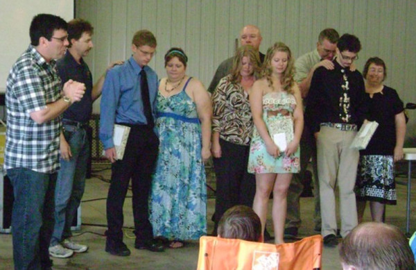 Mike Soltis (left) praying for graduates in May on Graduation Sunday.