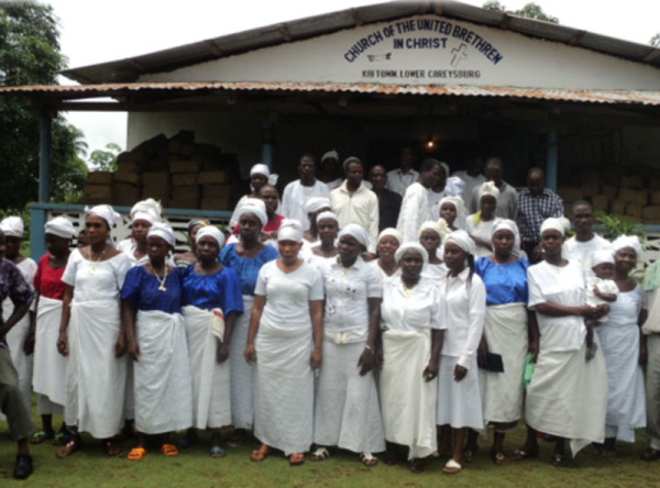 Members of one of the United Brethren churches in Liberia. Note the sign at the top of the church building.