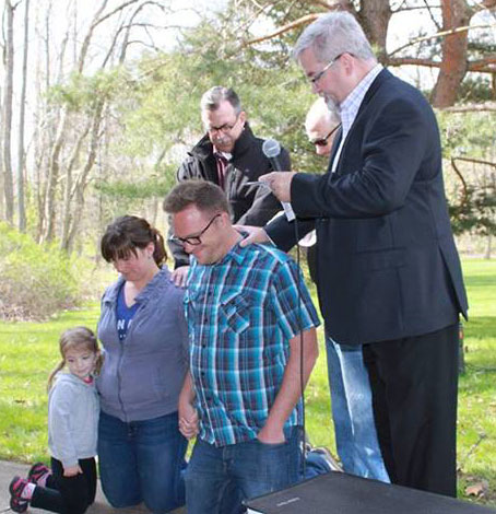Andy and Meri Sikorra kneel as Bishop Phil Whipple conducts Andy's ordination.